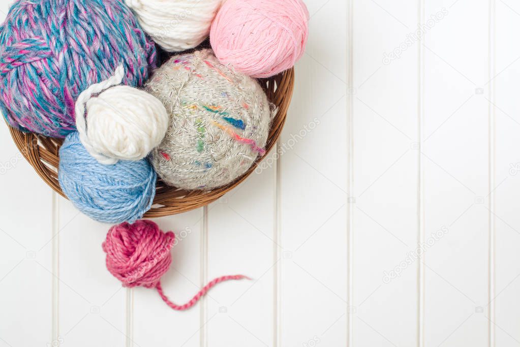 Knitting yarn balls and needles on white wooden background.