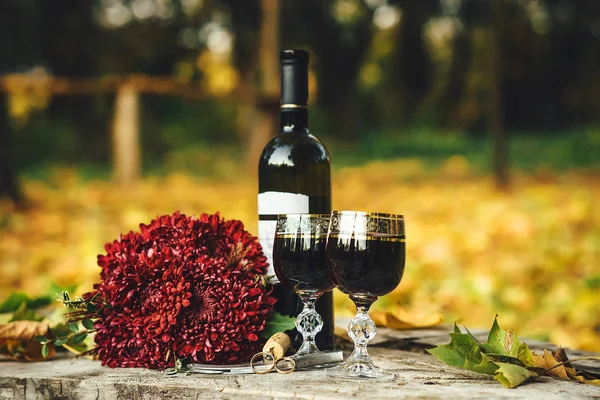 Trouwringen, glazen wijn, een boeket bloemen op het hout — Stockfoto