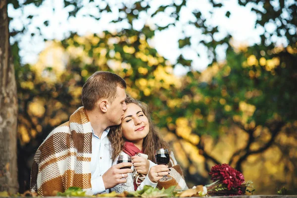 Liebespaar mit Weingläsern umarmt sich im Herbstpark. — Stockfoto