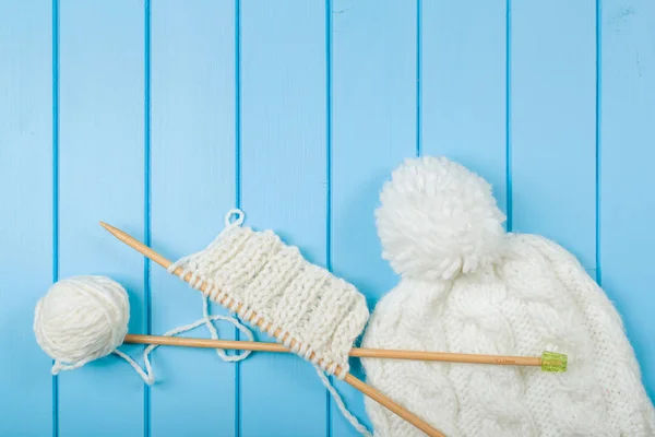 Bufanda blanca de punto y sombrero sobre fondo azul de madera . — Foto de Stock