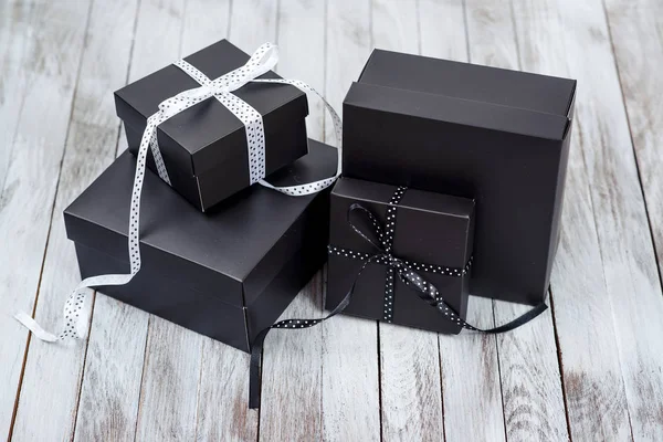 Cajas de regalo negras sobre fondo de madera . — Foto de Stock