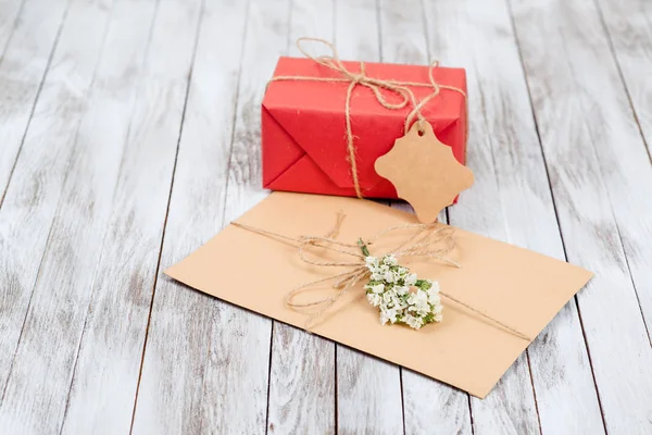Greeting letter and gift box with tag on wooden background. — Stock Photo, Image