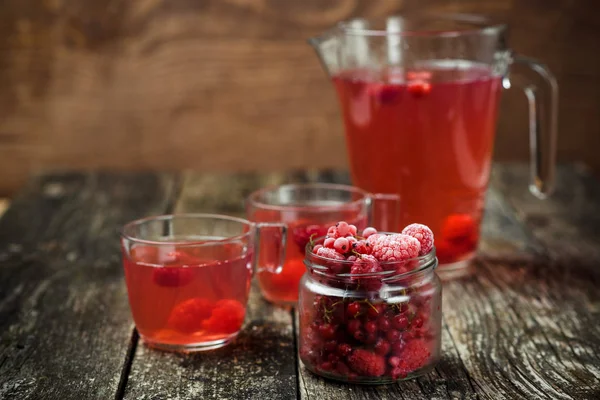 Berries compote in glass jar , two cup on wooden background. Selective focus. — Stock Photo, Image