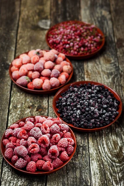 Frozen berries in bowls on wooden background. Selective focus. — Stock Photo, Image