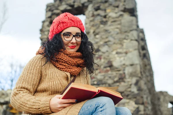 Krásná dívka číst knihu poblíž starého hradu. Podzimní čas. — Stock fotografie