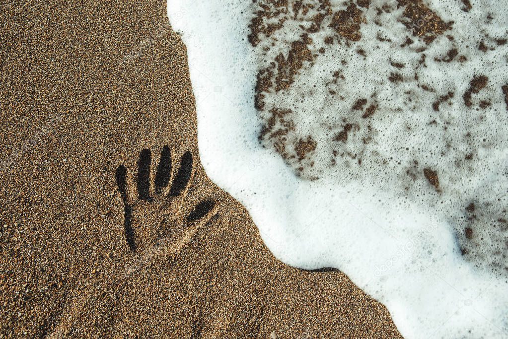 Print of the hand on sand.