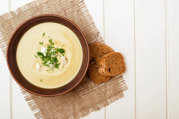 Beyaz ahşap masa üstünde Kremalı brokoli çorbası.