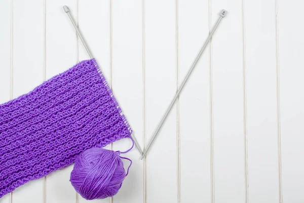 Knitting purple scarf close up on a wooden white table. — Stock Photo, Image