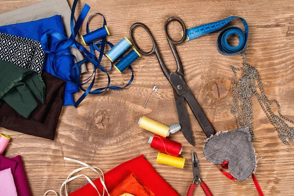 Cotton fabrics for sewing, spool of thread, scissors,measuring tape and accessories . Set for needlework. Top view.