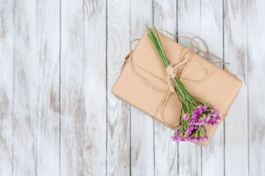 Eko stil hediye kutusu ahşap arka plan üzerinde kurutulmuş çiçekli. Üstten Görünüm.