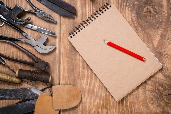 Set of tools, notebook, pencil for shoemaker on a wooden background. — Stock Photo, Image