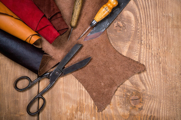 Set of leather craft tools on wooden background. Workplace for shoemaker.