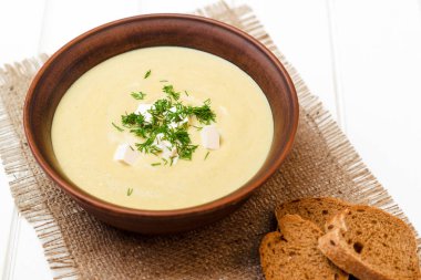 Beyaz ahşap masa üstünde Kremalı brokoli çorbası.