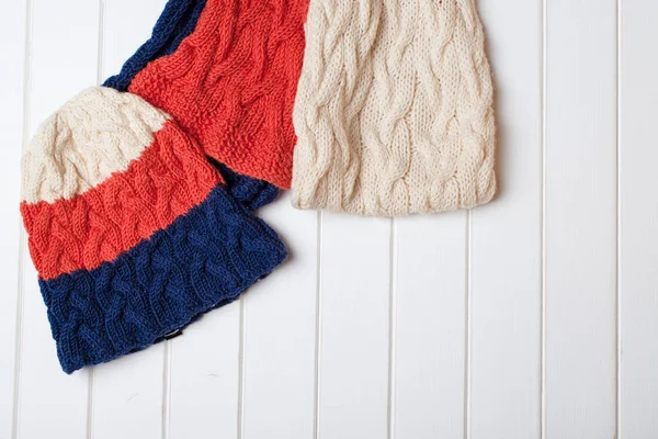Bunte Wollmütze und Schal auf weißem Holzgrund. — Stockfoto