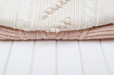 Beyaz ahşap zemin üzerinde iki modern örgü kazak.