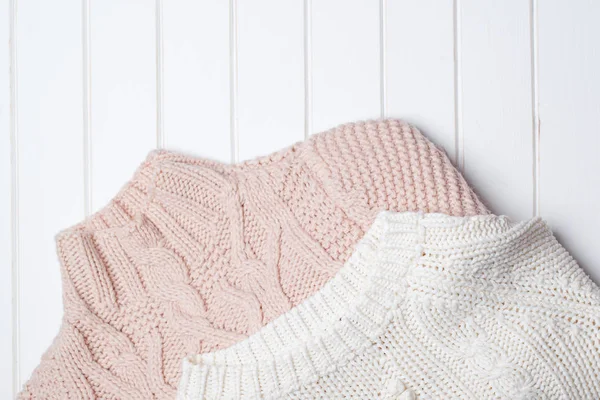 Two modern knitted sweaters on white wooden background. — Stock Photo, Image