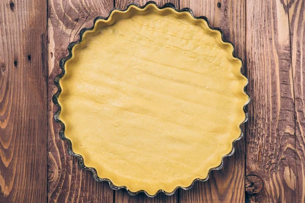 Hamur ahşap arka plan üzerinde pişirme formda. Ev yapımı pasta hazırlanıyor.