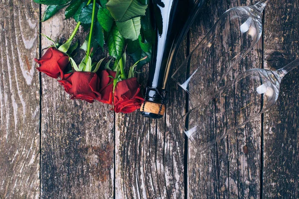 Bouquet de roses rouges, deux verres, bouteille de vin, coffret cadeau avec étiquette sur planche de bois vintage. Saint Valentin. Vue du dessus . — Photo