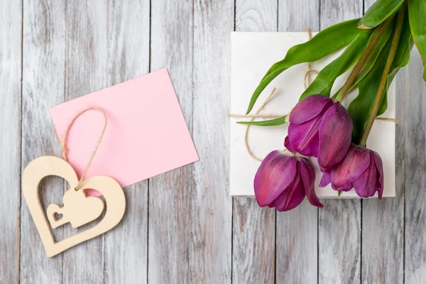 Fräsch lila tulpaner bukett och gåva rutan på trä bakgrund. Utrymme för text. Dekorativt hjärta. — Stockfoto