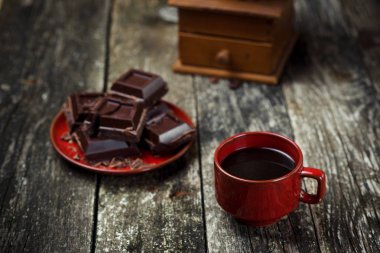 Kahve fincanı kırmızı, ahşap üzerinde çikolata parçalarını arka plan masa. Renkli. Seçici odak.