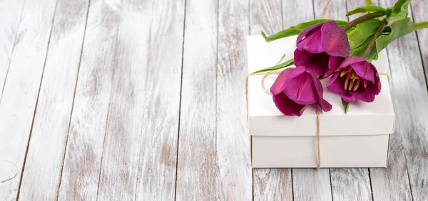 Fresh purple tulips bouquet and gift box on wooden background. Space for text. — Stock Photo, Image