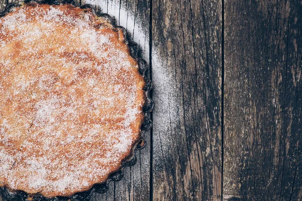 Homemade pie sprinkled with powdered sugar on rustic wooden background. Space for text. — Stock Photo, Image