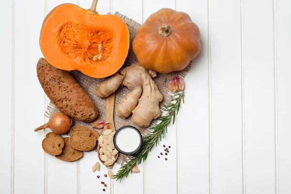 Calabaza e ingredientes para cocinar sobre fondo de madera blanca. Comida vegetariana, concepto de salud o cocina . — Foto de Stock