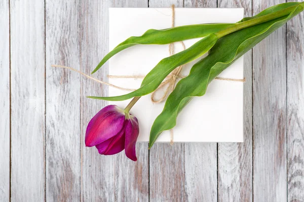 Bouquet di tulipani viola freschi e scatola regalo su sfondo di legno. Spazio per il testo. Vista dall'alto . — Foto Stock