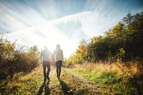 Una joven pareja caminando al aire libre tomados de la mano . —  Fotos de Stock