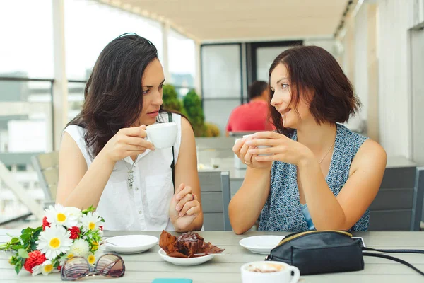 Дві усміхнені жінки мають чашку кави в кафе . — стокове фото