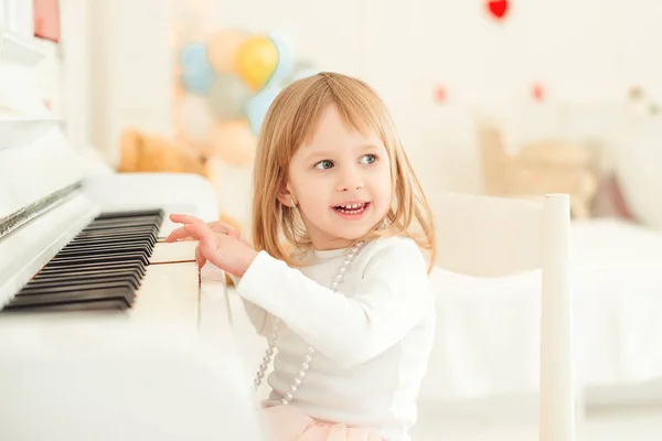 Niedliches kleines Mädchen spielt Klavier im hellen Raum. — Stockfoto