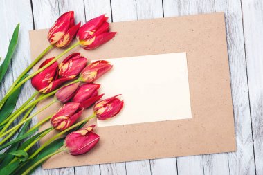 Güzel kırmızı lale, boş kağıt sayfası ahşap arka plan üzerinde. Anneler günü.