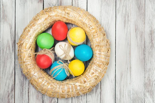 Oeufs de Pâques multicolores à l'intérieur couronne décorative sur fond en bois. Espace pour le texte . — Photo