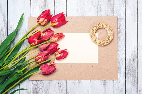 Lindas tulipas vermelhas, folha de papel vazia no fundo de madeira. Dia das mães . — Fotografia de Stock