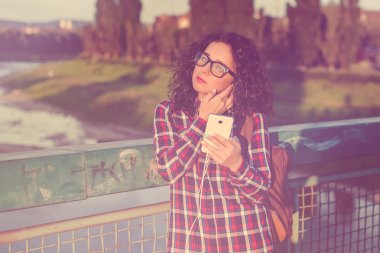 Genç kadın veya smartphone ve açık havada müzik kulaklık ile genç kız gülümsüyor. Tonda.