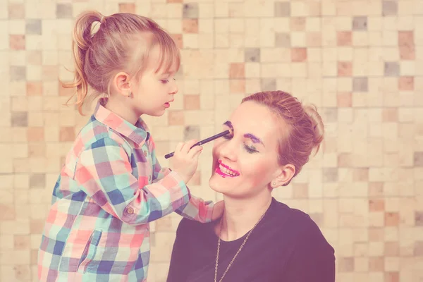 Roztomilá holčička dělá make-up pro její krásnou matku. Tónovaný. — Stock fotografie
