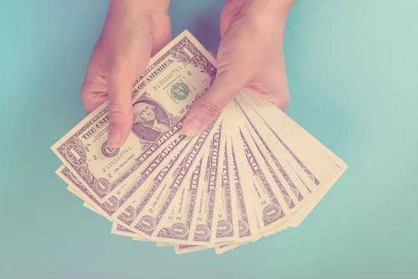Vrouwelijke handen met geld op een blauwe achtergrond. Economie-concept. Toewijzing van geld. Toned. — Stockfoto
