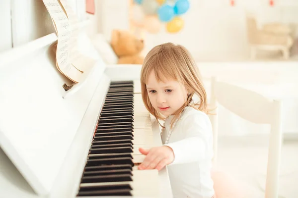 Cute little girl playing piano in light room. — Stock Photo, Image