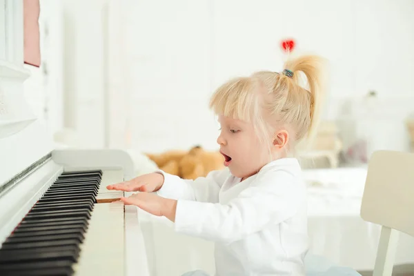 Schattig kind meisje pianospelen in een studio. — Stockfoto