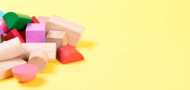 Sarı arka plan üzerinde renkli ahşap yapı taşları.