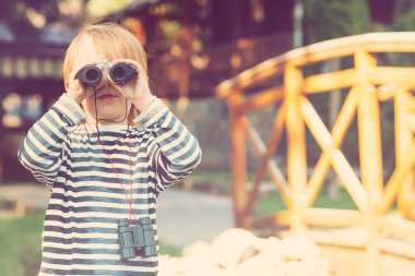 Sevimli küçük bir çocuk açık dürbün ile seyir.