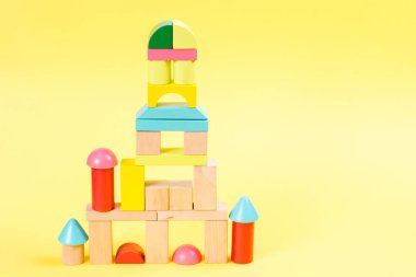 Sarı arka plan üzerinde renkli ahşap yapı taşları.
