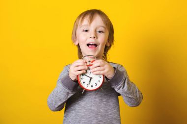 Sevimli küçük çocuk ile çalar saat Sarı zemin üzerine.
