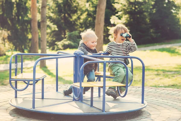 Zwei glückliche Jungen, die auf einem Spielplatz in einem Park spielen. gemildert. — Stockfoto