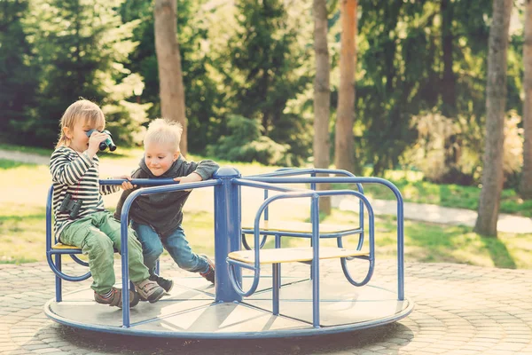 Zwei glückliche Jungen, die auf einem Spielplatz in einem Park spielen. gemildert. — Stockfoto