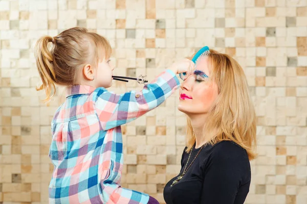 Söt liten flicka gör makeup och frisyr för sin vackra mor. — Stockfoto