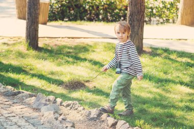 Sevimli çocuk dışarıda oynarken elinde tahta sopa ile. Çocukluk.