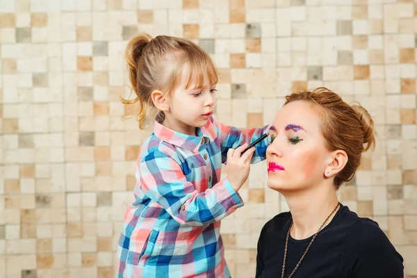 Niedliche kleine Mädchen machen Make-up für ihre schöne Mutter. — Stockfoto
