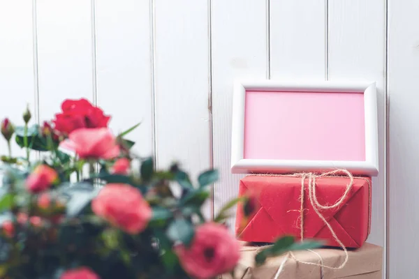 Hermosas rosas en una olla con una tarjeta de felicitación en blanco sobre fondo de madera rústico blanco . — Foto de Stock