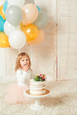 Doğum günü pastası ve renkli balonlar içinde Oda mutlu küçük kız.